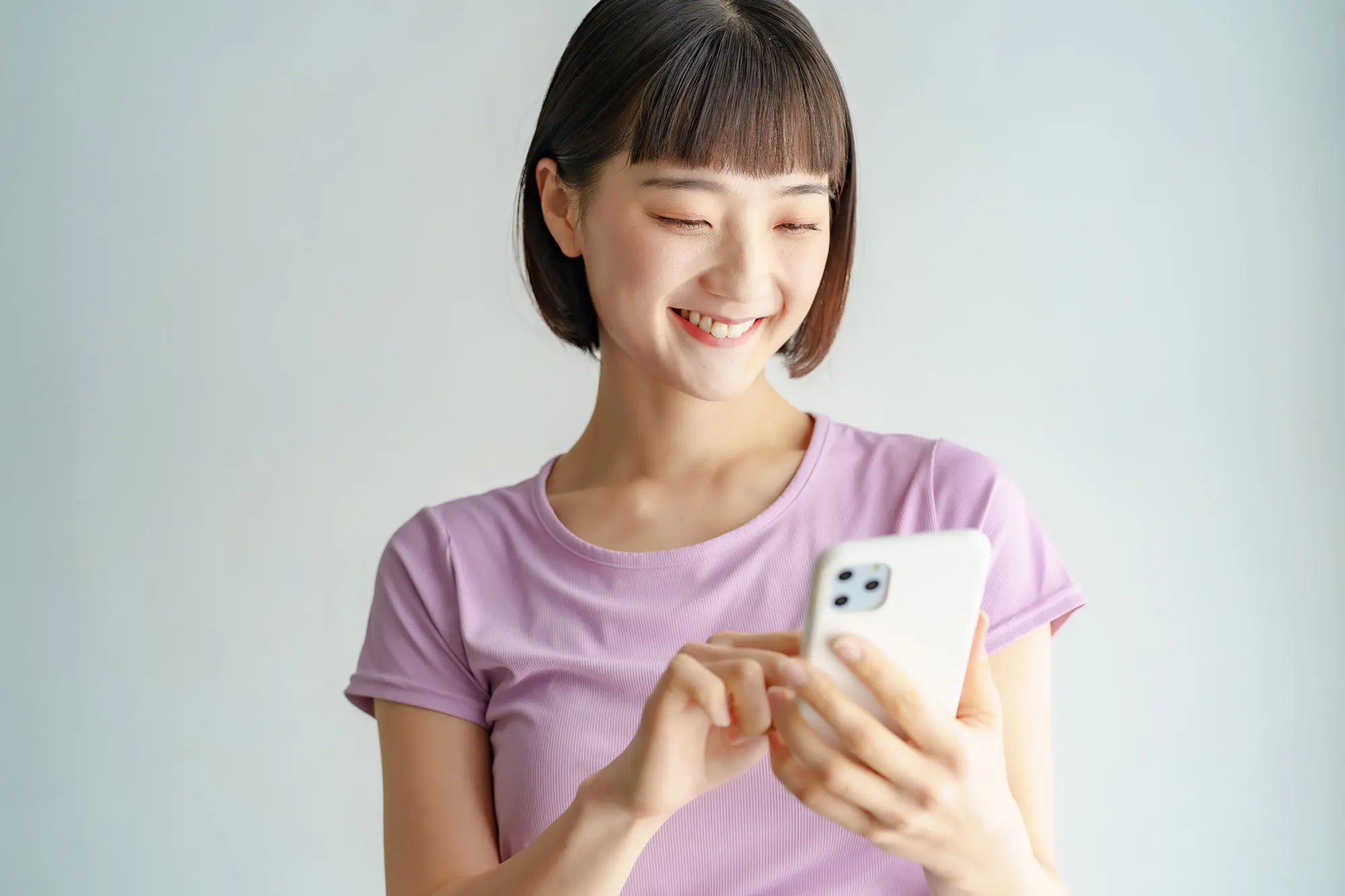FAQ Frequently asked questions. Smiling woman looking at her phone.